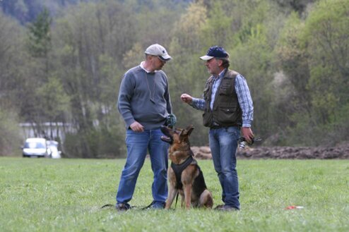 Thorsten Funk spricht mit Kunden davor sitzt ein schäferhund und blickt zuhöhrend nach oben